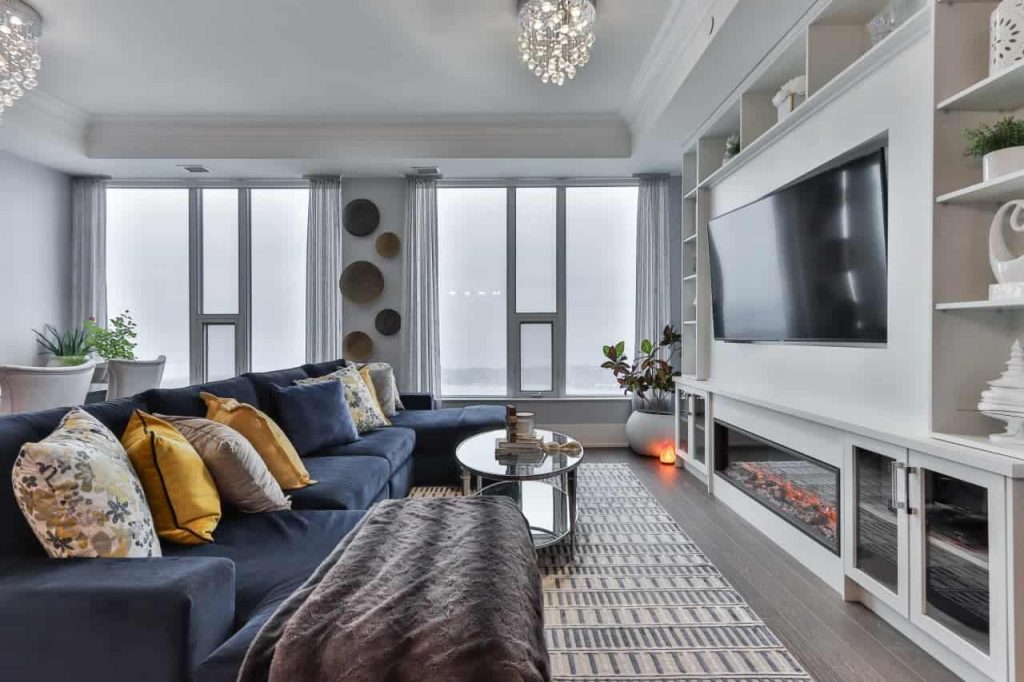 A living room with sustainable property management practices, featuring a fireplace and large windows, advanced property