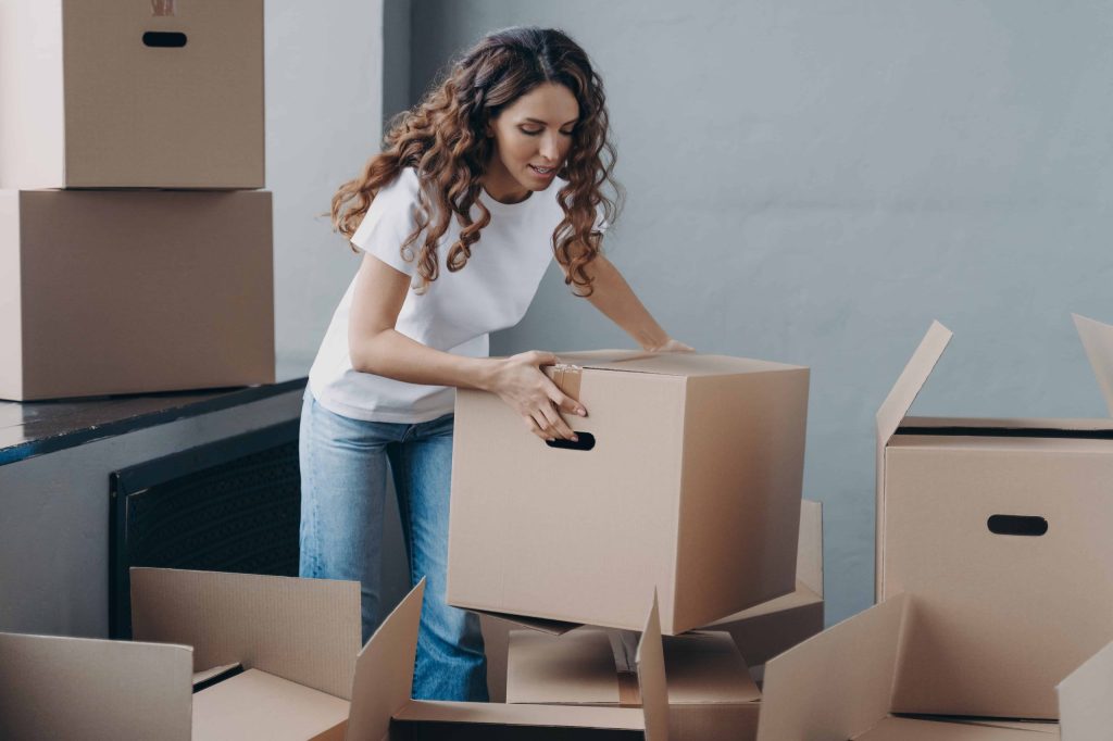 A woman managing tenants while unpacking boxes in a room.