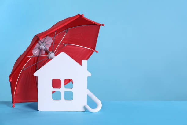 A red umbrella with a house model on a blue background for property management insurance, real property management service