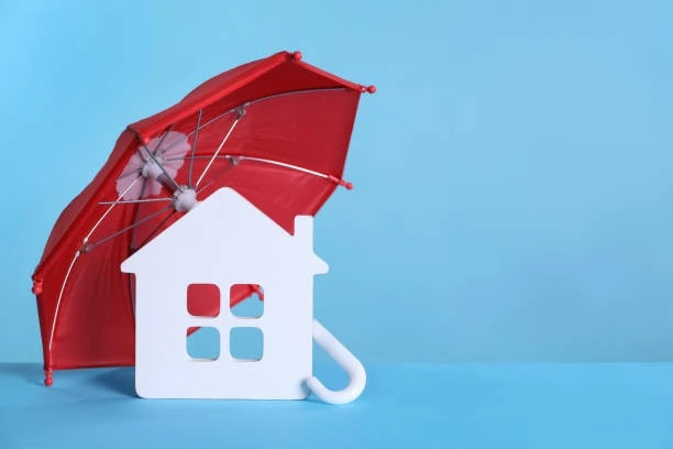 A red umbrella with a house model on a blue background for property management insurance.