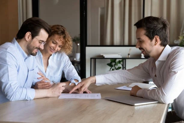 Consultant presenting a rental property security document to a smiling couple during a meeting.