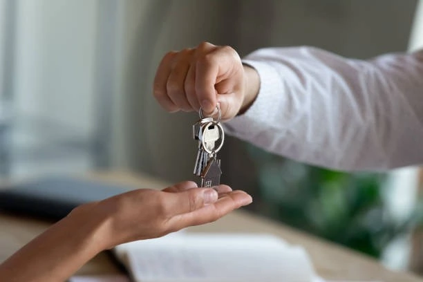 A person employing tenant retention strategies hands a key to another person.