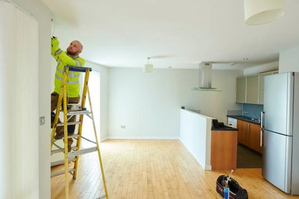A man working on a ladder in a kitchen for a Property Management Company.