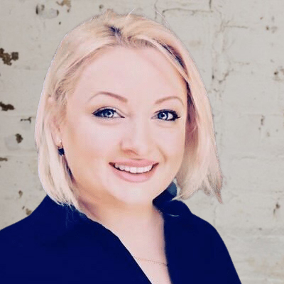 Portrait of a smiling woman with short blonde hair, representing the best property management company, wearing a dark blazer, against a textured beige background.
