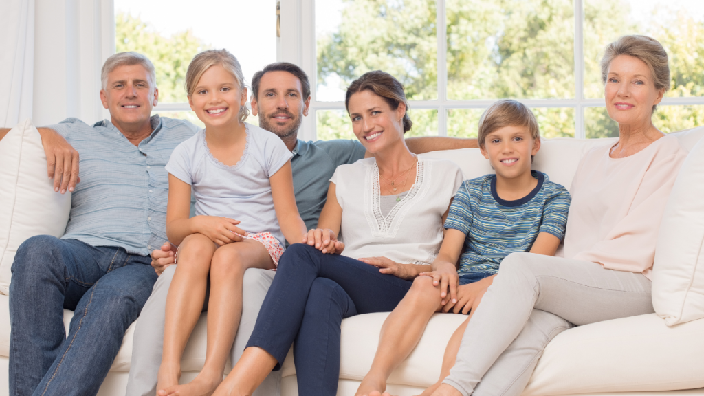 A three-generation family, content in their tenant satisfaction, posing together on a couch, smiling at the camera in a bright living room, good property management companies