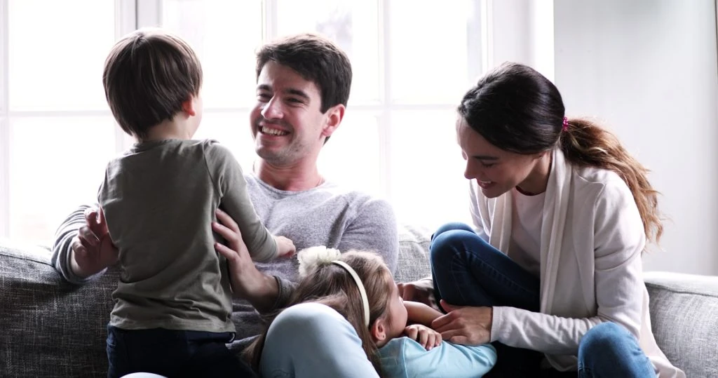 Family enjoying a moment together on a comfortably spacious couch, a detail that helps increase tenant satisfaction.