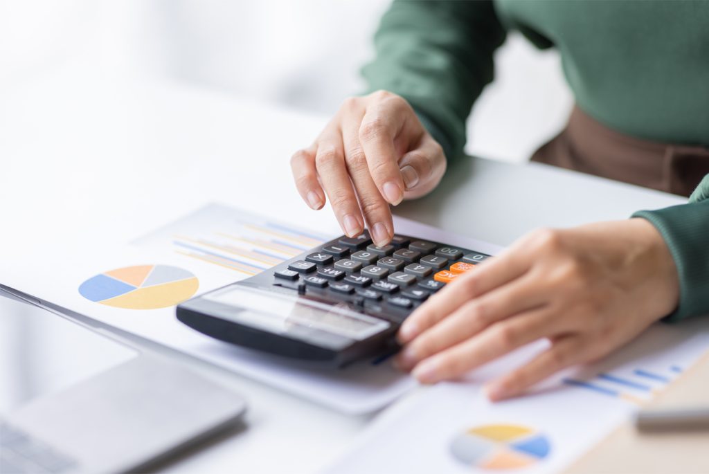 In the competitive property rental market, a woman is focusedly using a calculator on her desk to crunch numbers and make informed financial decisions, property manager Hamilton Canada