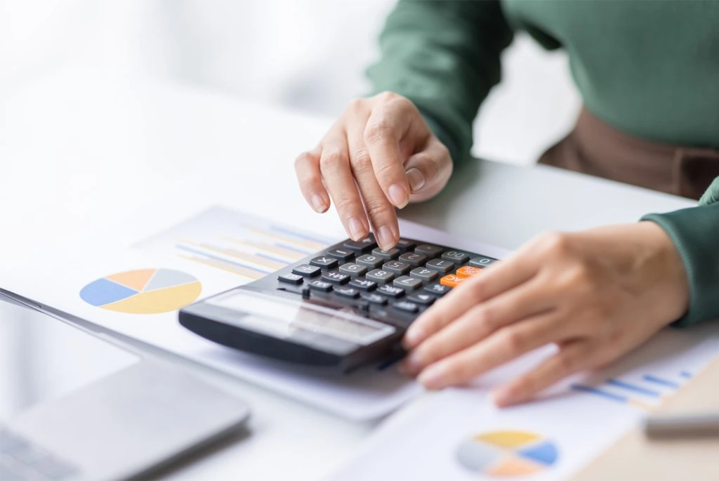 In the competitive property rental market, a woman is focusedly using a calculator on her desk to crunch numbers and make informed financial decisions.
