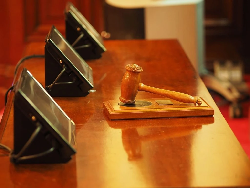 A judge's gavel, symbolizing authority and order, sits on a table in a courtroom.