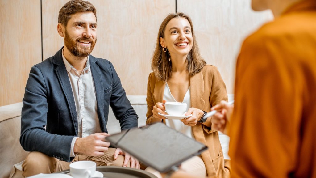 A man and a woman are enjoying their coffee in a coffee shop, engaging in casual conversation.
