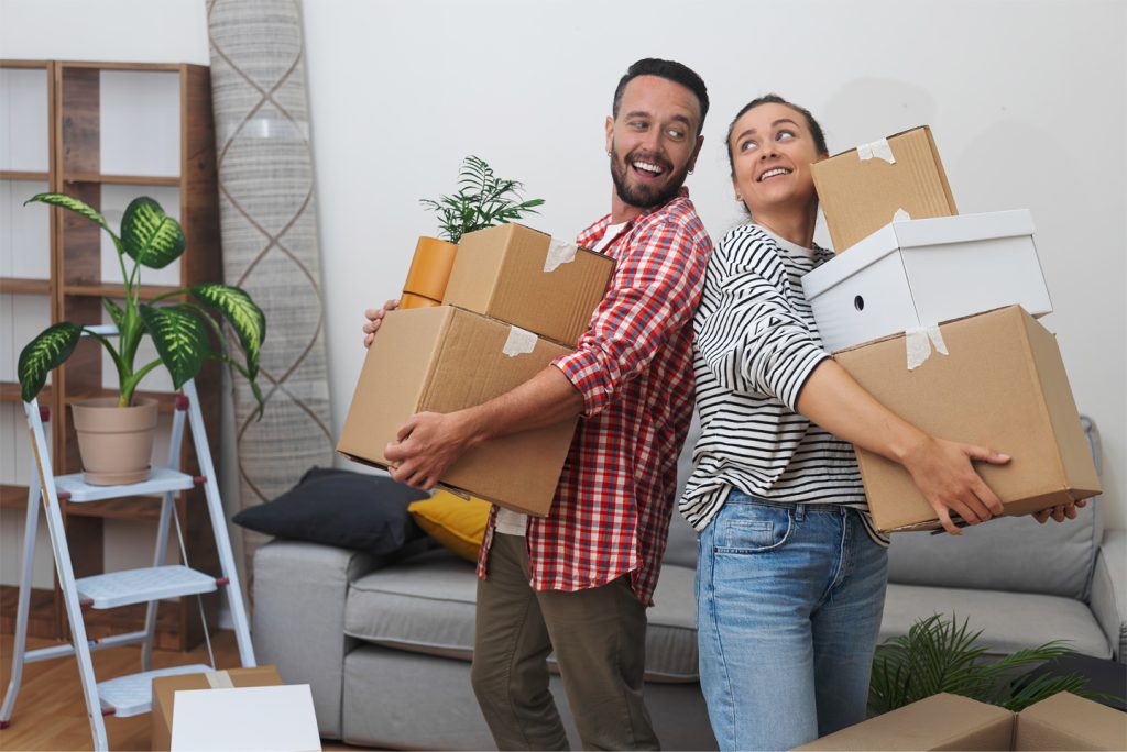 A young couple embracing boxes in their new home, undergoing tenant improvement, property rental management companies