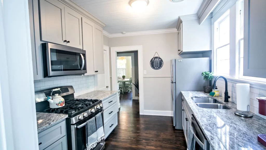 A kitchen with gray cabinets and a stove is perfect for Airbnb property management.