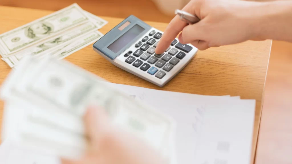 A hand holding a calculator calculating rental property management fees.