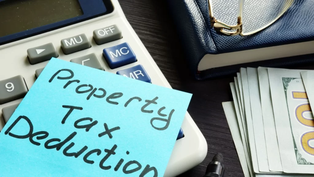 A note with the words "property tax deduction" sitting on top of a calculator, reminding you that certain expenses like rental property management fees may be tax deductible.