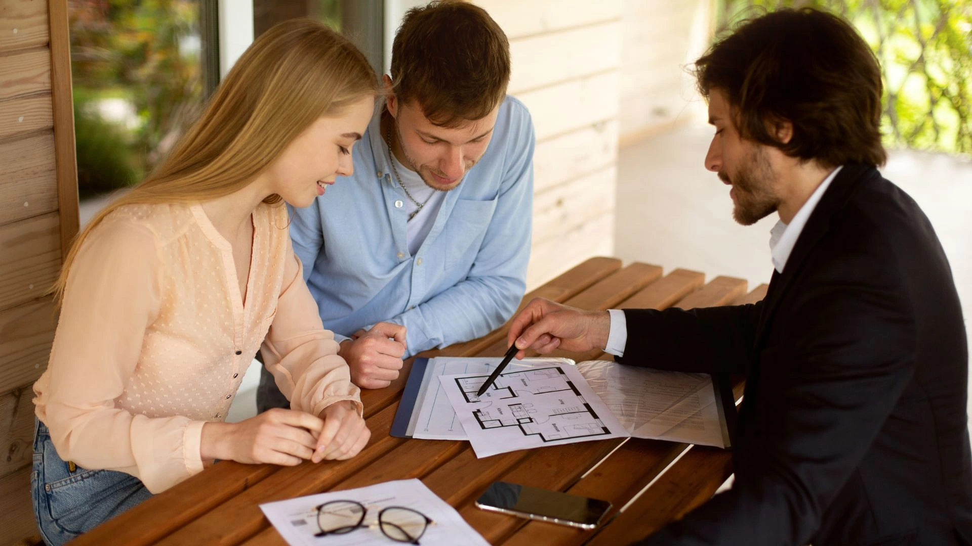 Three people sitting at a table examining a house plan for Property Management, residential property management services