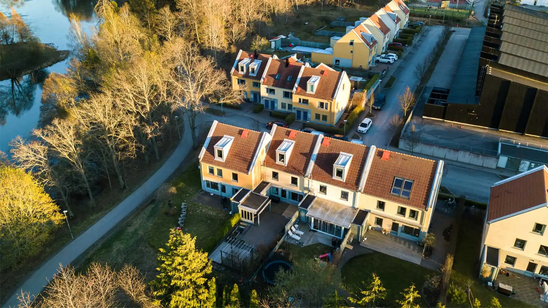 Aerial view of residential houses with brown roofs, surrounded by trees and a road running along the edge of the neighborhood, showcasing some of the best property management in Kitchener.