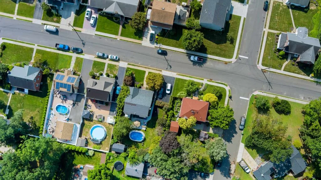 Aerial view of pet friendly rentals in a residential neighborhood with houses, pools, and vehicles on a sunny day.