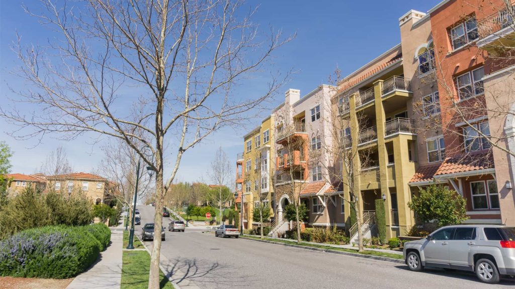 Suburban street with modern apartment buildings and parked cars on a sunny day, showcasing the future of property management, Best Property Management in Hamilton, Rental Property Management Services
