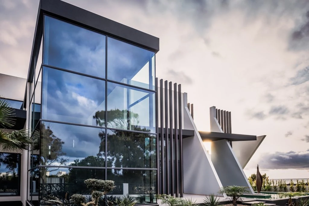 Modern building with large glass windows and abstract architectural features, surrounded by landscaping, epitomizes the future of property management under a cloudy sky.