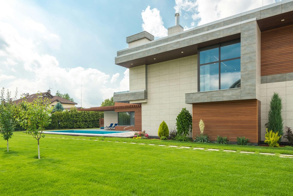 Modern two-story house with large windows, surrounded by a manicured lawn and trees, boasting exceptional curb appeal. The backyard features a swimming pool for endless enjoyment, hamilton property management company