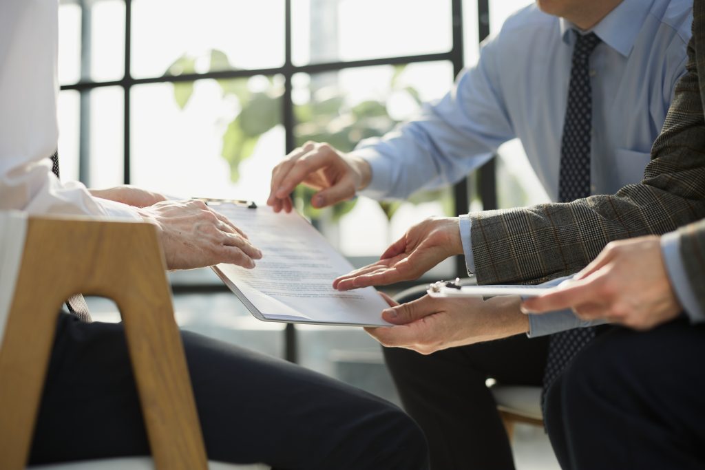 closeup business deal meeting businessman carefully reviewing terms condition contract agreement papers office