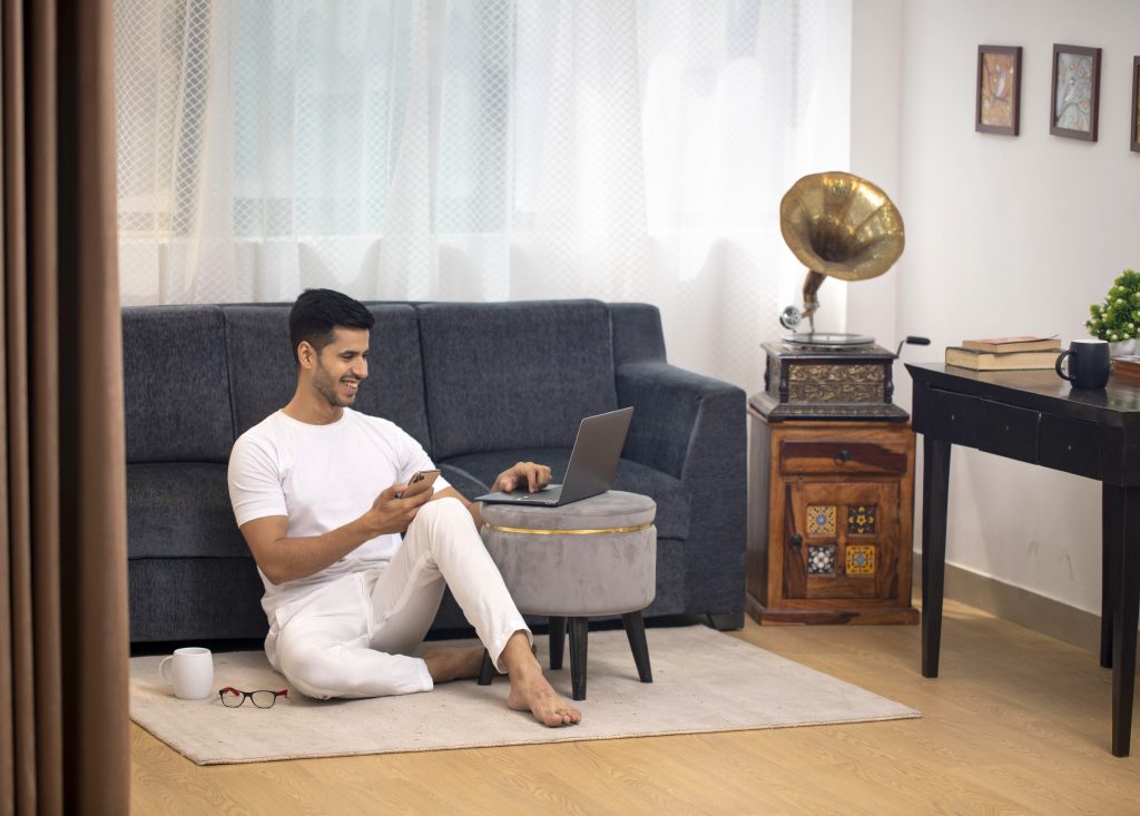 man sits rug with laptop coffee table