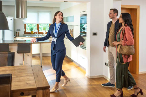 A real estate agent shows a modern kitchen to a man and woman during a home tour, highlighting features that make renting with pets easy and comfortable.
